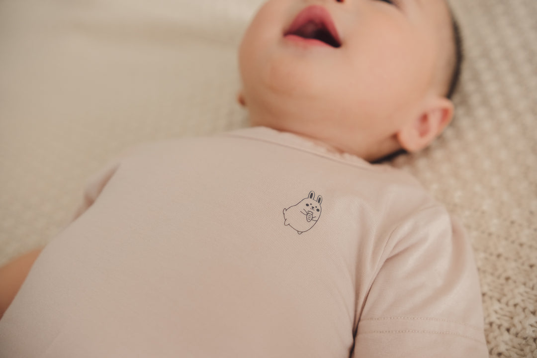 Close-up of a baby wearing a beige onesie, highlighting the design details