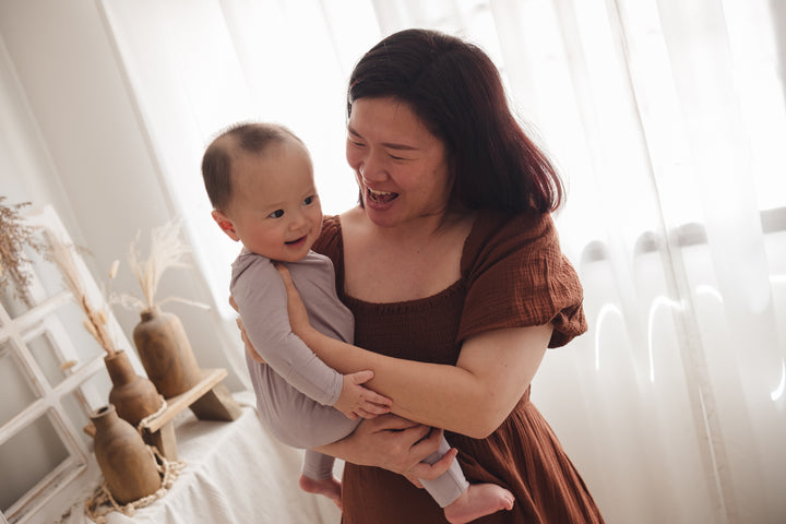 Mother holding her baby in her arms, baby wearing a lavender sleep suit