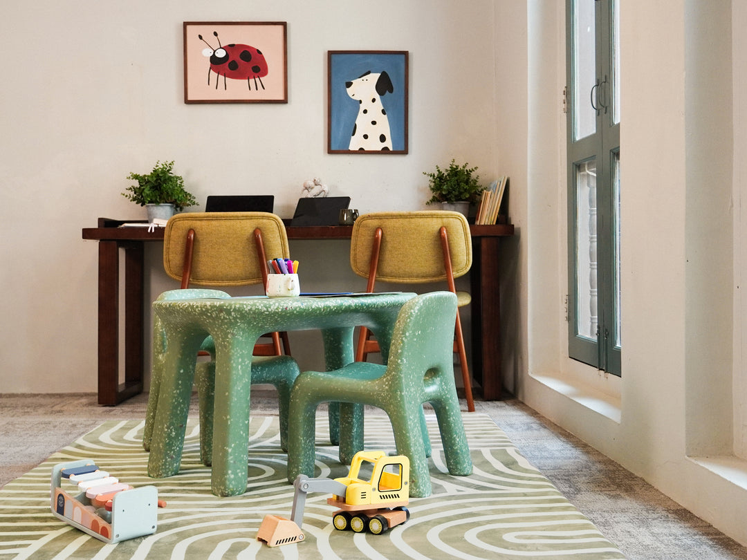 A cosy study corner featuring a green speckled table and matching chairs placed on the patterned Lollibly Kaya Plush Playmat.