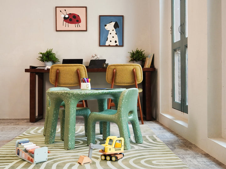 A cosy study corner featuring a green speckled table and matching chairs placed on the patterned Lollibly Kaya Plush Playmat.