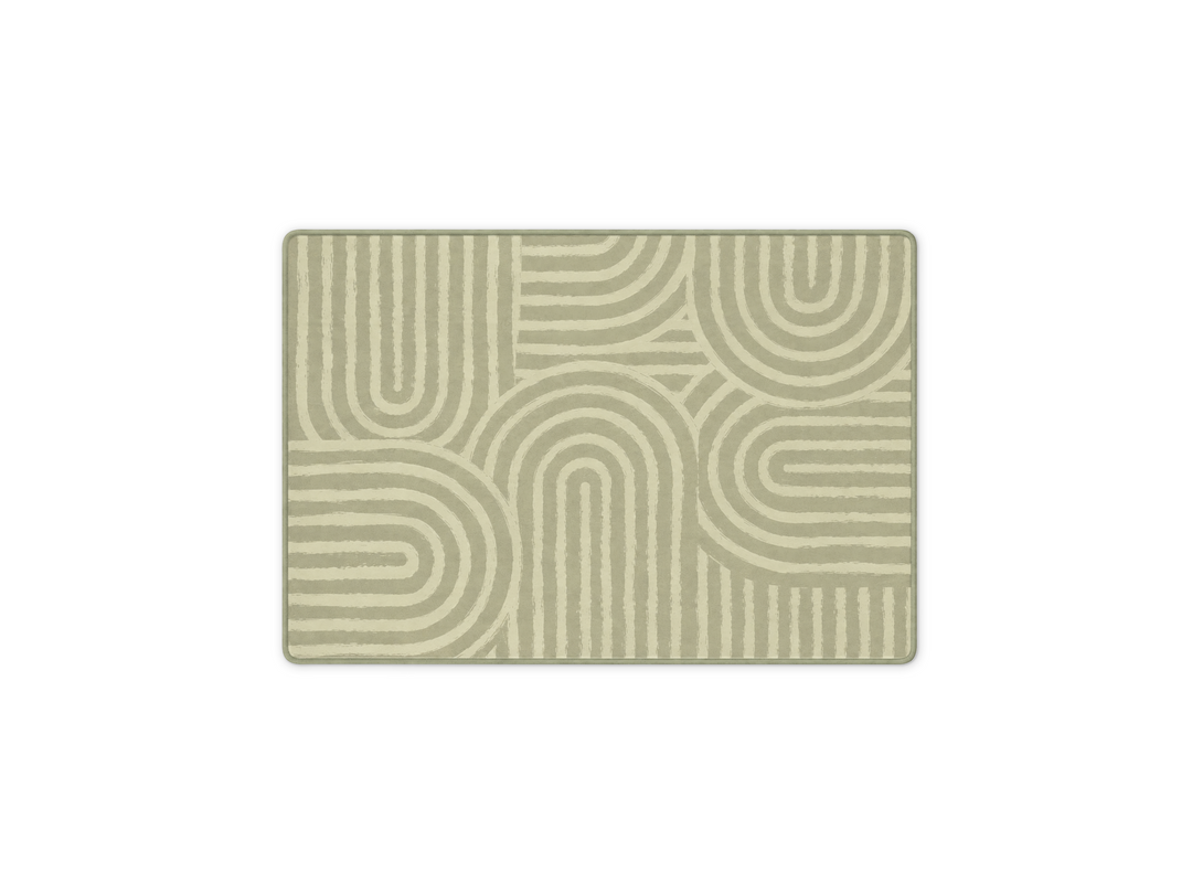 Lollibly Kaya Plush Playmat in Little One (100 × 140cm). A rectangular area rug with a modern geometric pattern of concentric arches and lines in sage green and cream.
