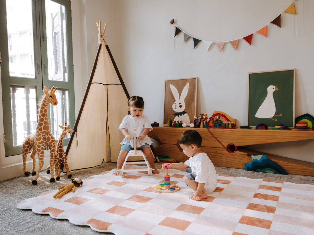 Two children playing together on the Lollibly Waffle Plush Playmat, featuring a checkered design in a cosy playroom.