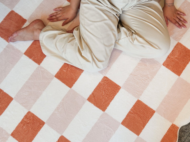 A person sitting comfortably cross-legged on the Lollibly Waffle Plush Playmat.